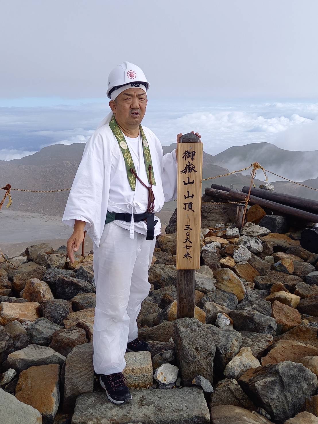 御嶽山山頂の標柱のそばに立つ丸岩天祥代表の一色重利