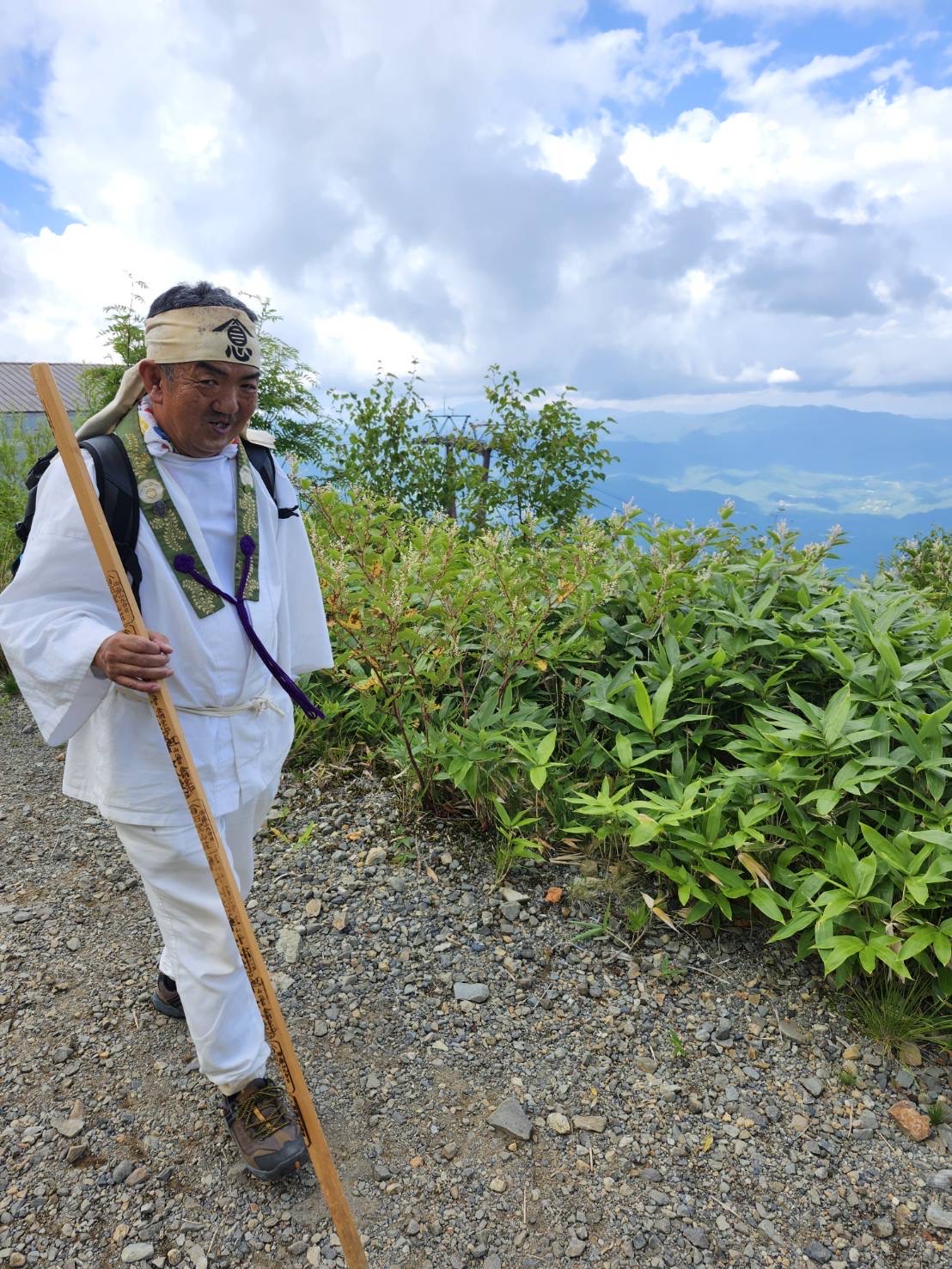御嶽山の山道を杖を持って歩く丸岩天祥代表の一色重利